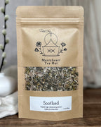 Kraft paper tea bag from Merryheart Tea Hut with visible herbs on a wooden surface.